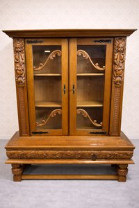 Masívna vitrína s vyrezávanými postavami a dekoratívnymi prvkami