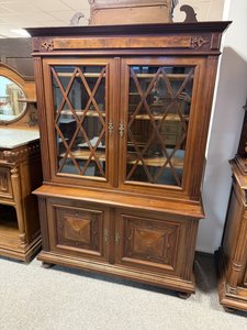 Vitrína s jemne tvarovanou rímsou a zdobenými dvierkami