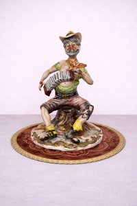 Porcelánová soška hudobníka s harmonikou