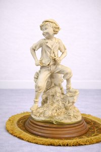 Porcelánová soška chlapca na skalke
