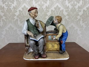 Porcelánová figurálna soška dedka a chlapca pri gramofóne s hodinovým strojčekom